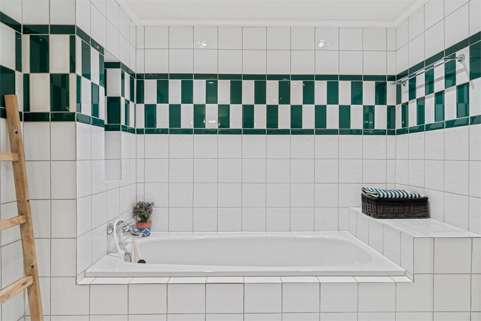 Innbygget badekar omkranset av flislagte flater.