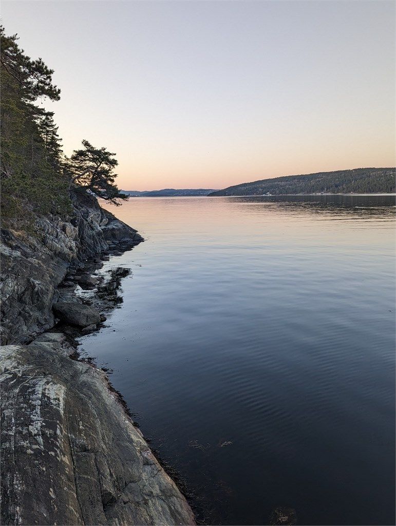 Egen brygge i vakker solnedgang, der varme fargetoner speiler seg i vannet og skaper en rolig og stemningsfull atmosfære (selgers bilde)