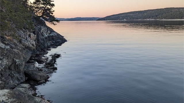 Egen brygge i vakker solnedgang, der varme fargetoner speiler seg i vannet og skaper en rolig og stemningsfull atmosfære (selgers bilde)
