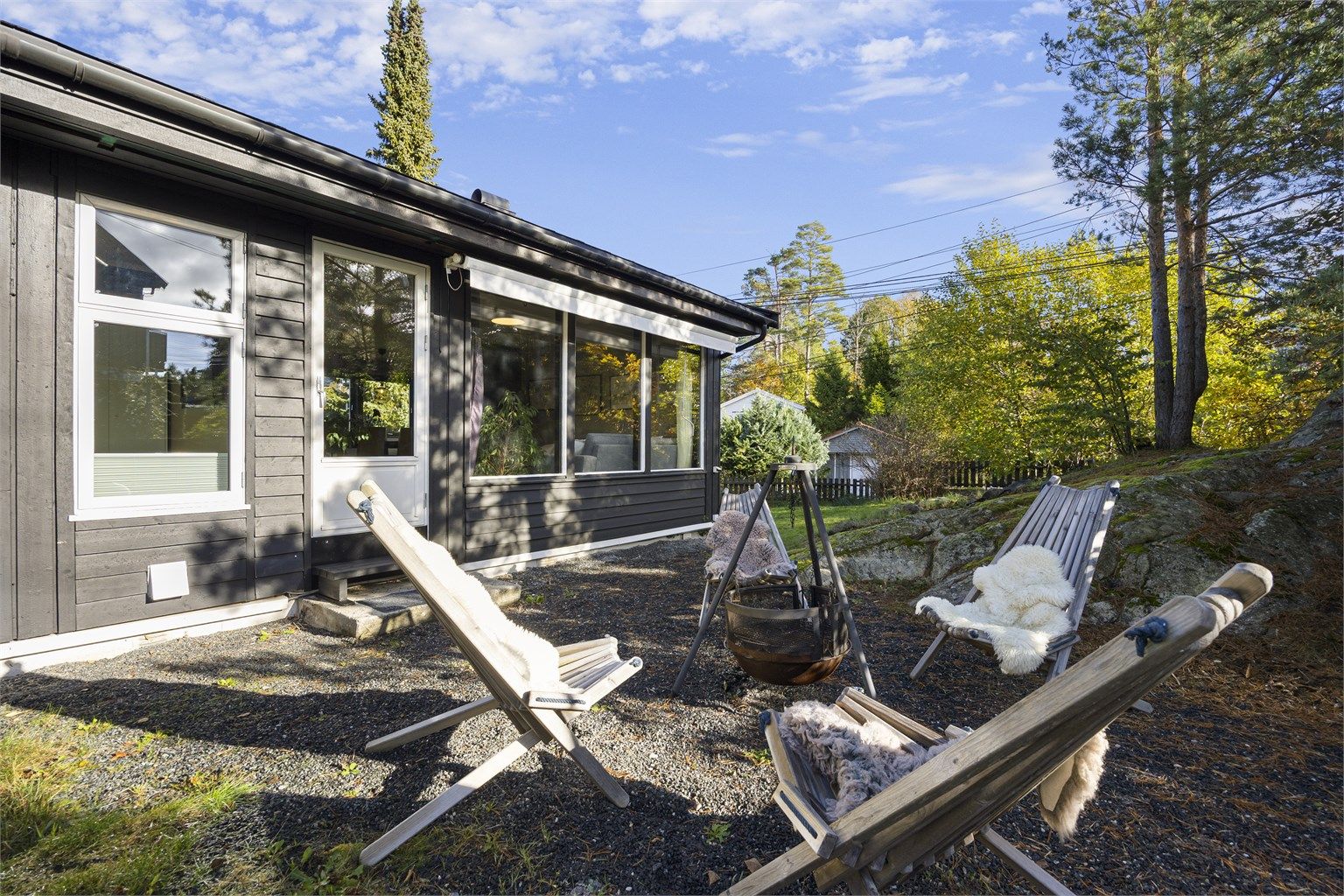 Opparbeidet uteplass i hagen med plass til bålpanne og sittegruppe. Elektrisk markise mot stue i hovedetasjen.