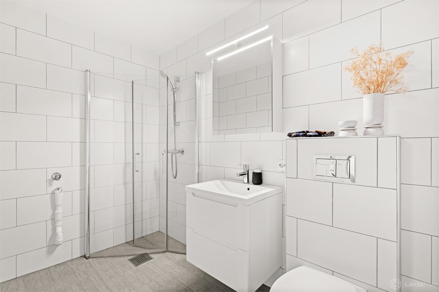 Bad i direkte tilknytning til kjellerstuen med moderne innredning, gulvvarme og praktisk opplegg for vaskemaskin.