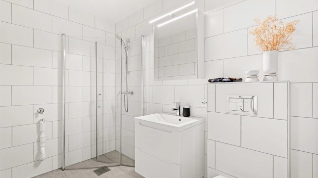 Bad i direkte tilknytning til kjellerstuen med moderne innredning, gulvvarme og praktisk opplegg for vaskemaskin.