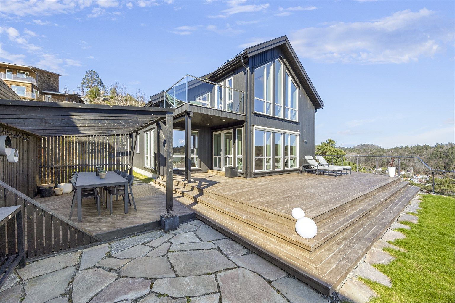 Boligen har en moderne arkitektur med stående trekledning og store vindusflater.