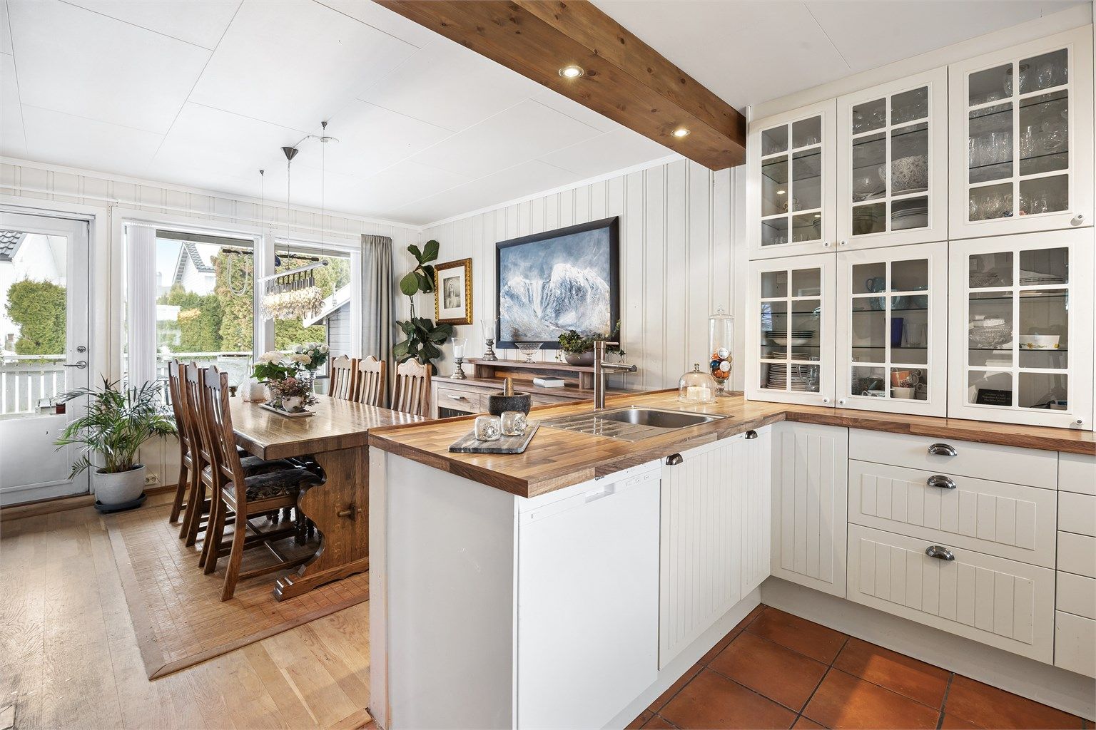 Profilert kjøkkeninnredning med underskap og vitrineskap i hvit utførelse.