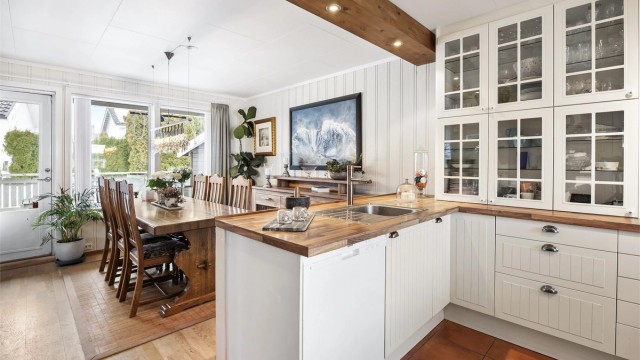 Profilert kjøkkeninnredning med underskap og vitrineskap i hvit utførelse.