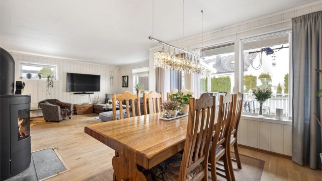 Lys vinkelstue med sofaområde og spiseplass.