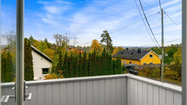 Utsyn fra balkongen over grønne nærområder og tomten.
