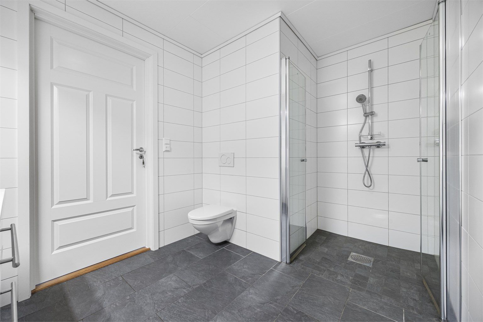 Badet har vegghengt toalett og opplegg for vaskemaskin.