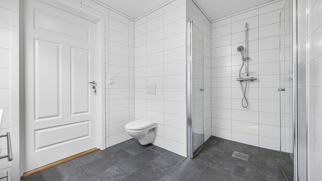 Badet har vegghengt toalett og opplegg for vaskemaskin.