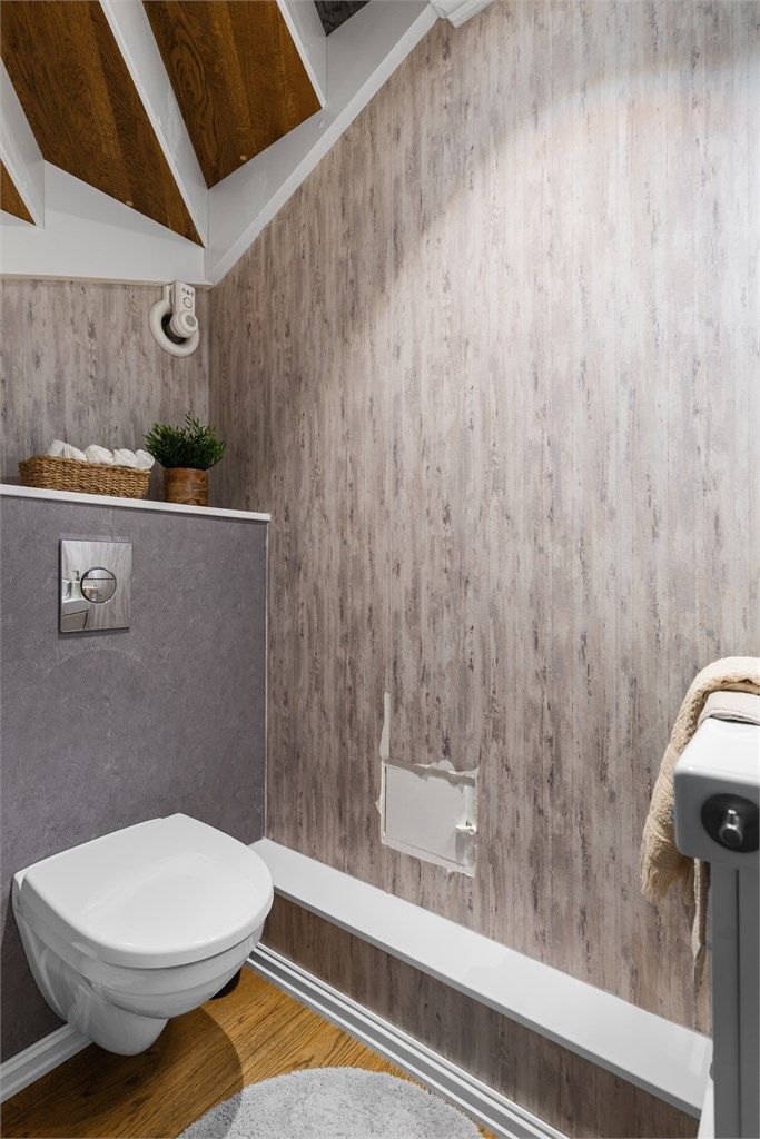 
Gjestewc ligger ved entré og har parkett på gulv, vegghengt toalett, tapet på vegg og enkel servant.