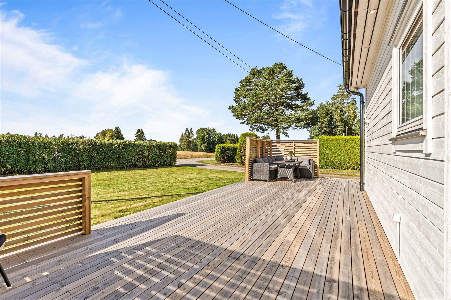 Solrik terrasse med god plass til utemøbler og åpen overgang til hagen.