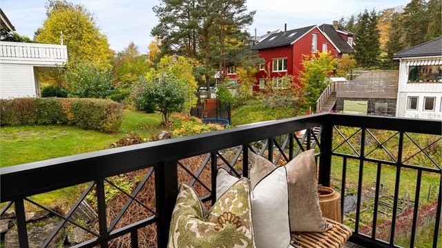 Balkong i 2. etasje med tremmegulv og smijernsrekkverk, med utgang fra hovedsoverommet.