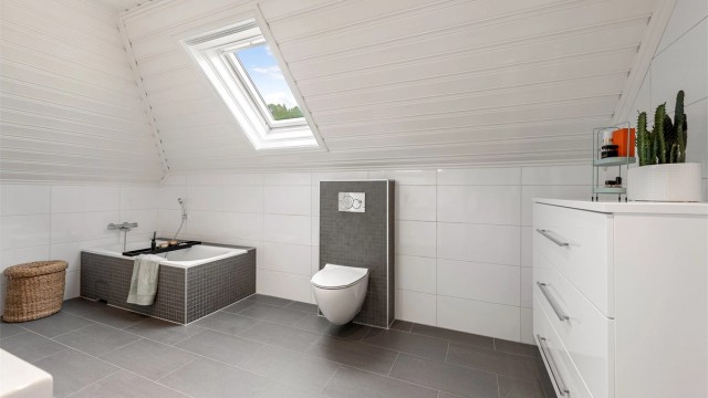 Badet på loft har innebygget badekar og vegghengt toalett. Gode lysforhold fra takvindu.
