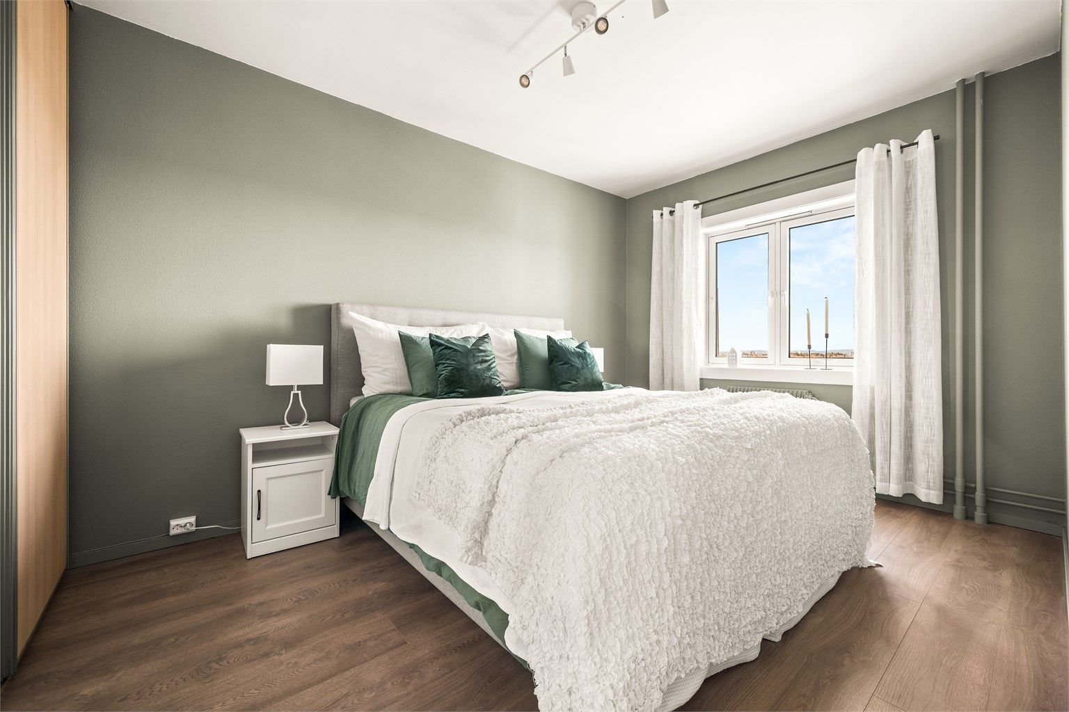 Romslig soverom med plass til dobbeltseng og nattbord.