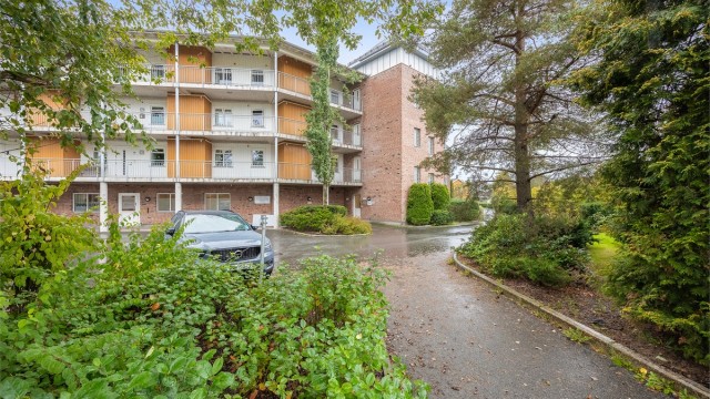 Bygning oppført i tegl og tre med velstelte grøntarealer rundt.