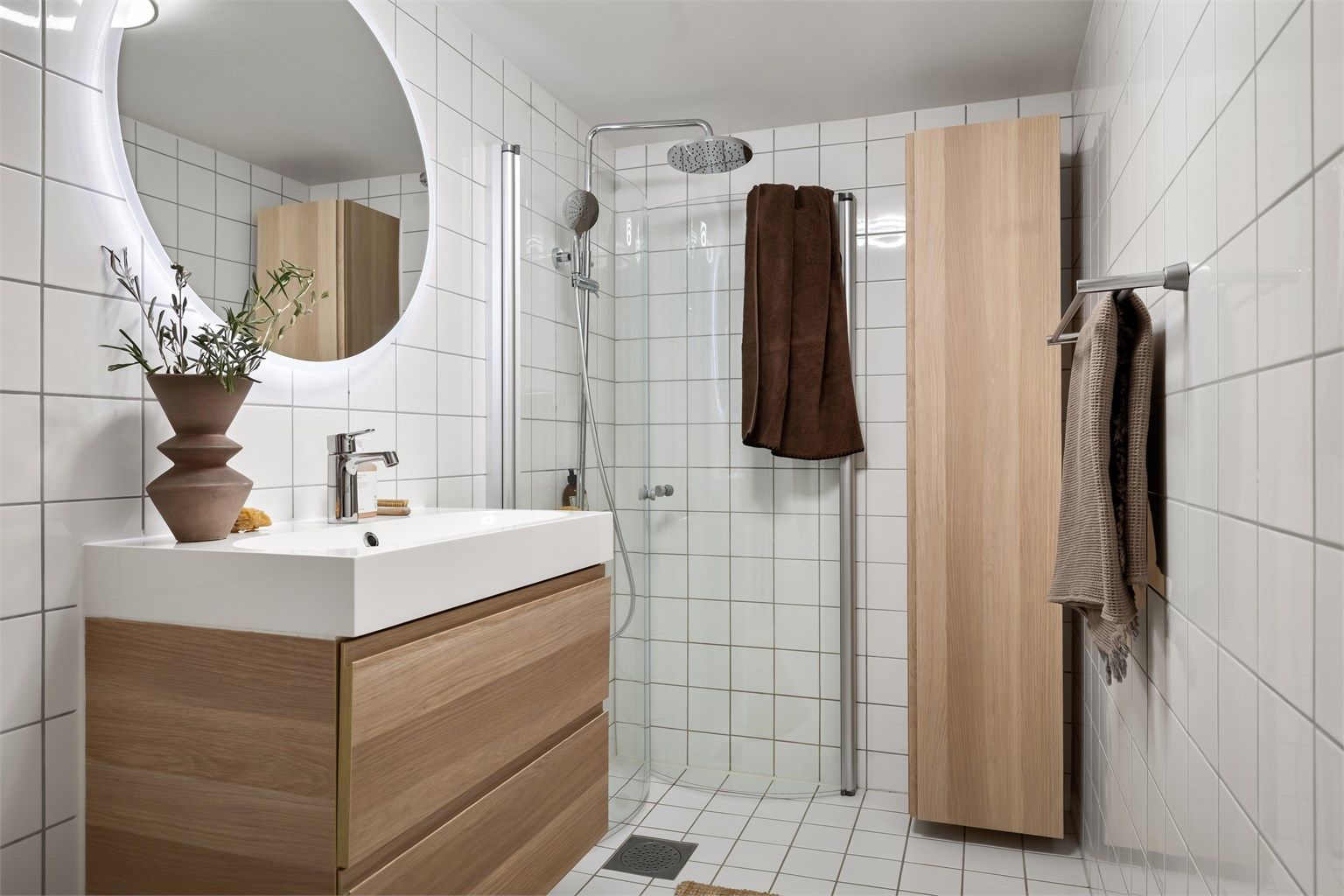Badet er utstyrt med vegghengt toalett og dusjhjørne med innfellbare glassdører, og dusjsett med rainshower