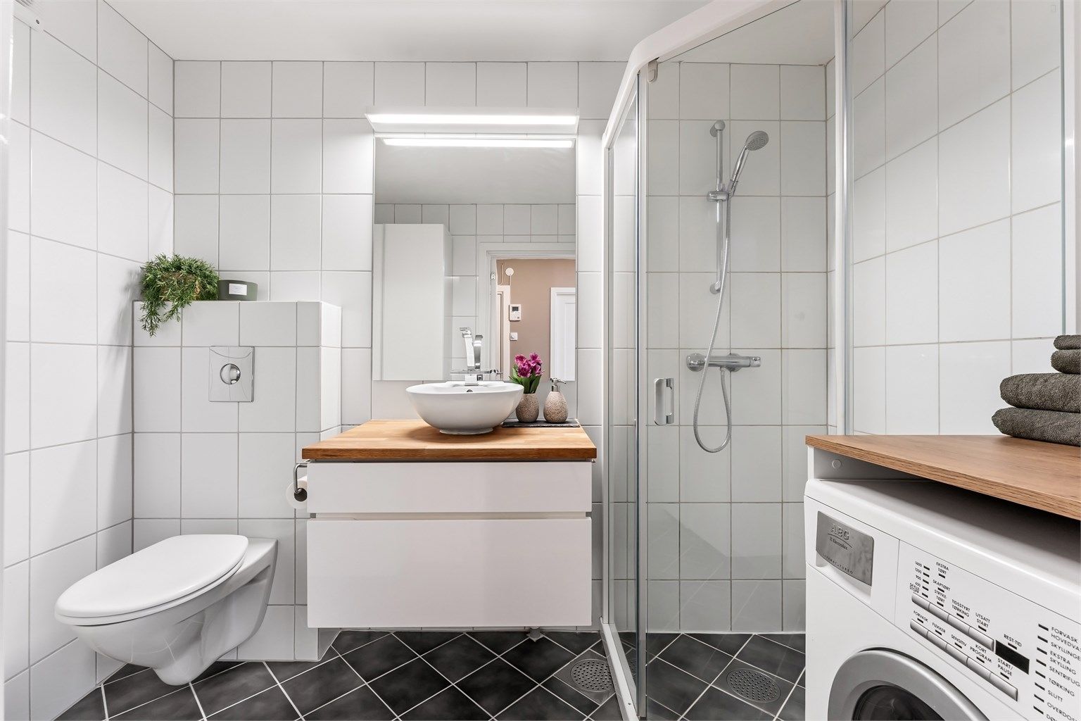 Badet har veggmontert toalett med innbygd sisterne og ny termostat for gulvvarme fra 2022.