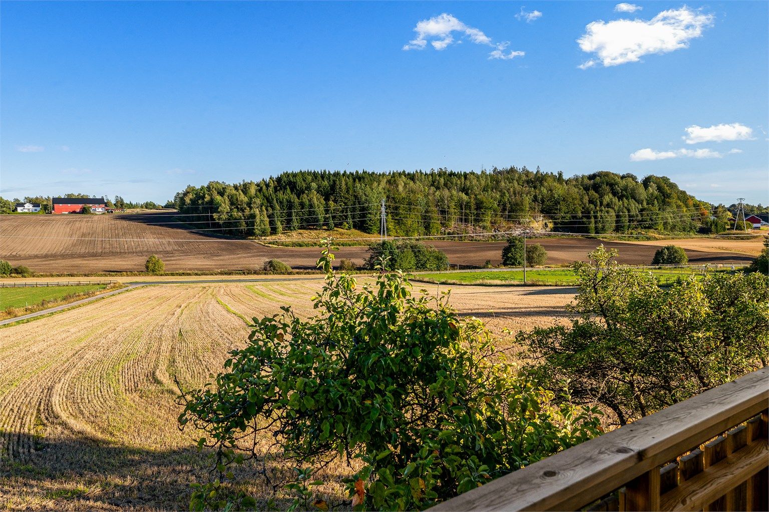 Utsikt fra balkongen utover de vidstrakte åkrene og skogkledde åsene.