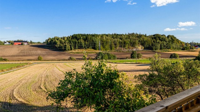 Utsikt fra balkongen utover de vidstrakte åkrene og skogkledde åsene.