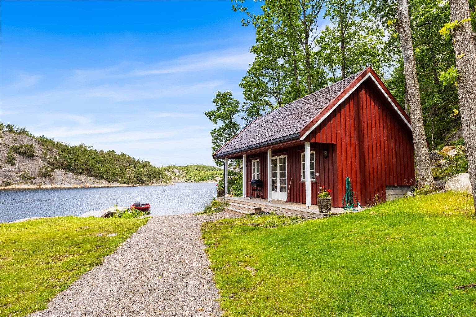 Nyoppført sjøbu med en liten terrasse og utsikt utover landskapet