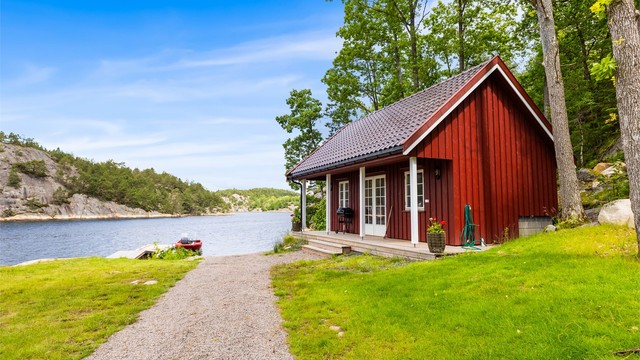 Nyoppført sjøbu med en liten terrasse og utsikt utover landskapet