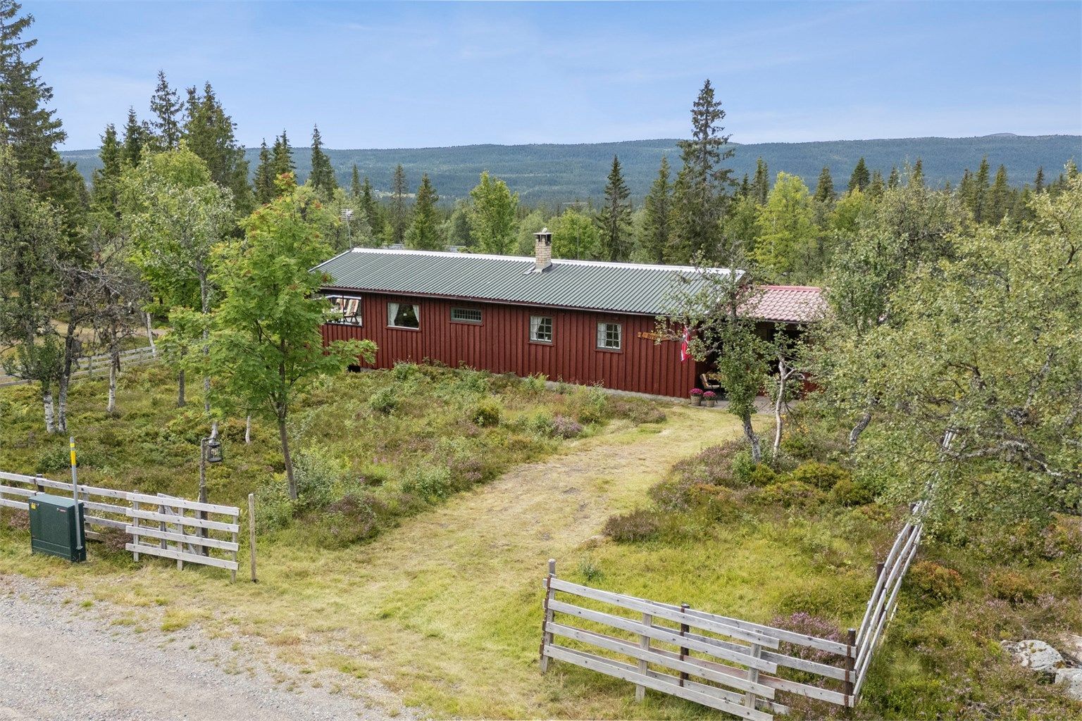 Hyggelig natureiendom med gressvokst innkjøring. Fremsiden av tomta er inngjerdet. 