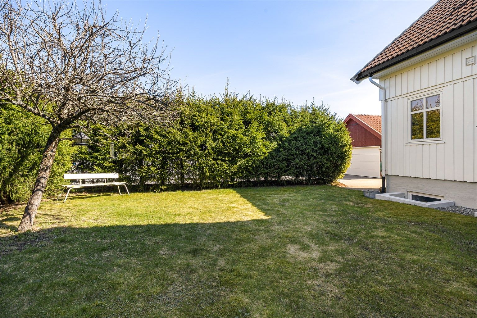 Hagen er pent opparbeidet med plenarealer og beplantning som skaper en privat og lun atmosfære.