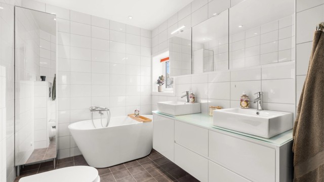 Badet i andre etasje er fra byggeåret, med flislagt gulv med gulvvarme og flislagte vegger.