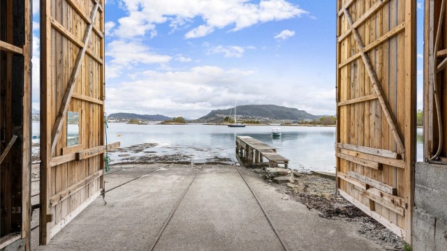 De brede portene gir en sømløs overgang mellom naustet og sjøen.