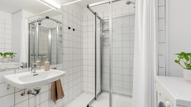 Flislagt bad med hvite veggfliser og lyse malte gulvfliser med gulvvarme.