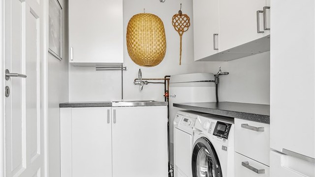 Separat vaskerom med innredning, utslagsvask og opplegg for vaskemaskin samt tørketrommel under benk.