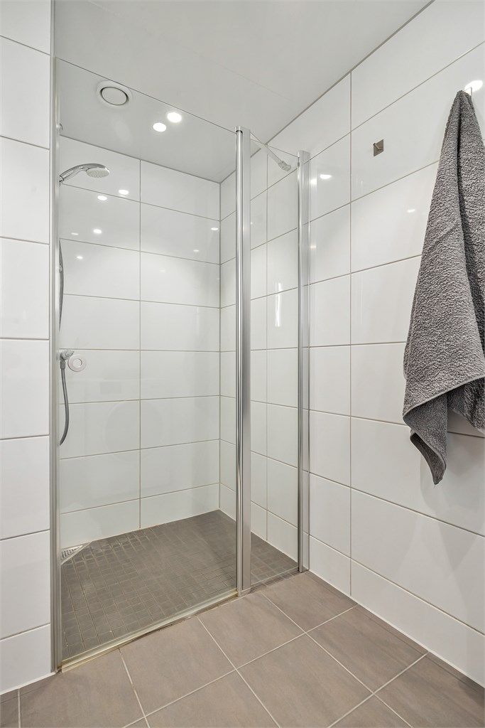 Badet har dusjnisje med dusjvegg-/dør av glass samt vegghengt dusjarmatur.