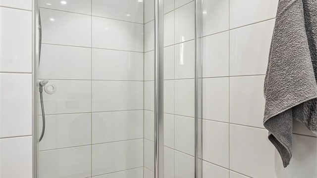 Badet har dusjnisje med dusjvegg-/dør av glass samt vegghengt dusjarmatur.