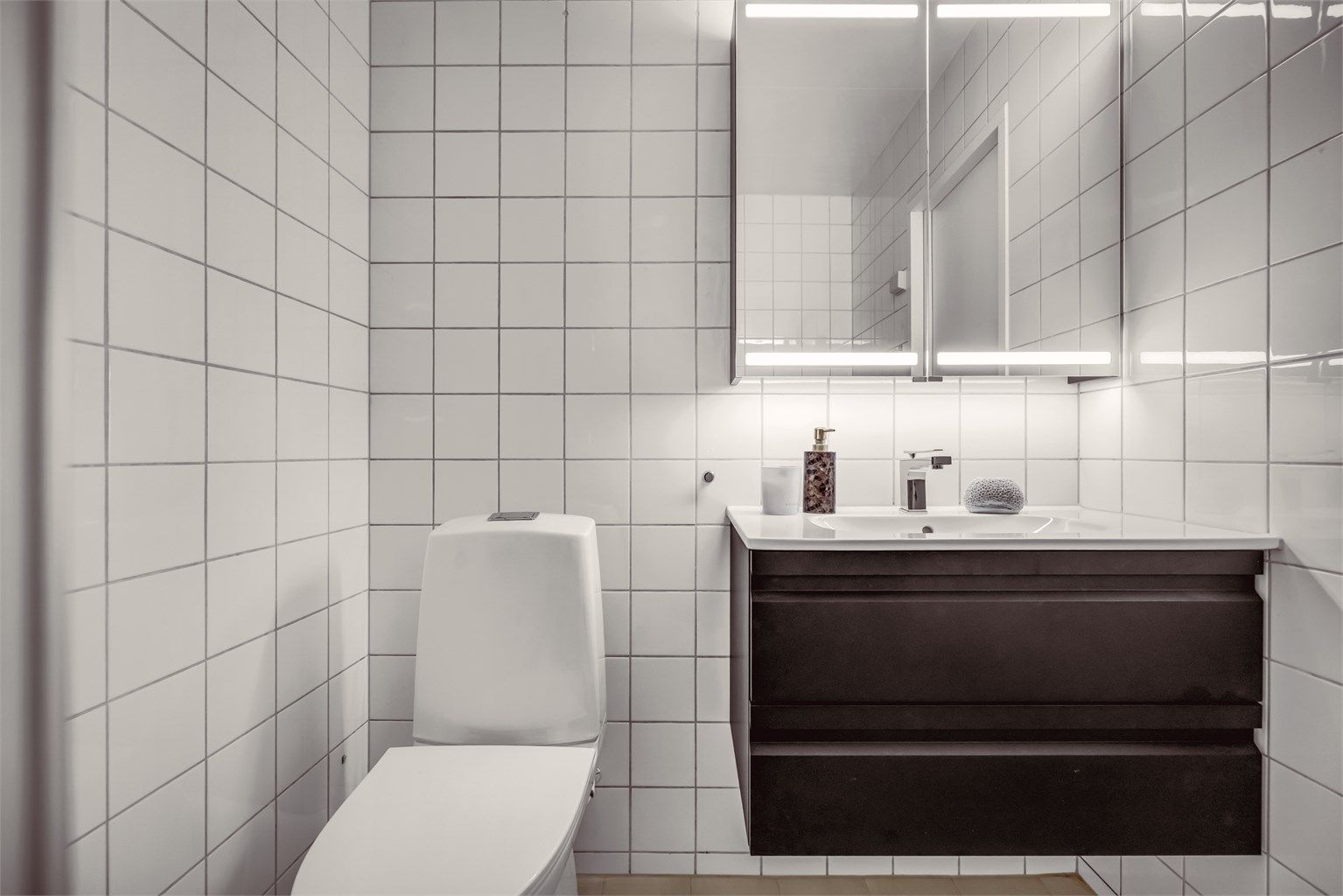 Badet har behagelig gulvvarme og er innredet med servantinnredning med skuffer, speil med overlys og stikkontakt over servanten. Gulvstående toalett.