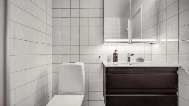 Badet har behagelig gulvvarme og er innredet med servantinnredning med skuffer, speil med overlys og stikkontakt over servanten. Gulvstående toalett.