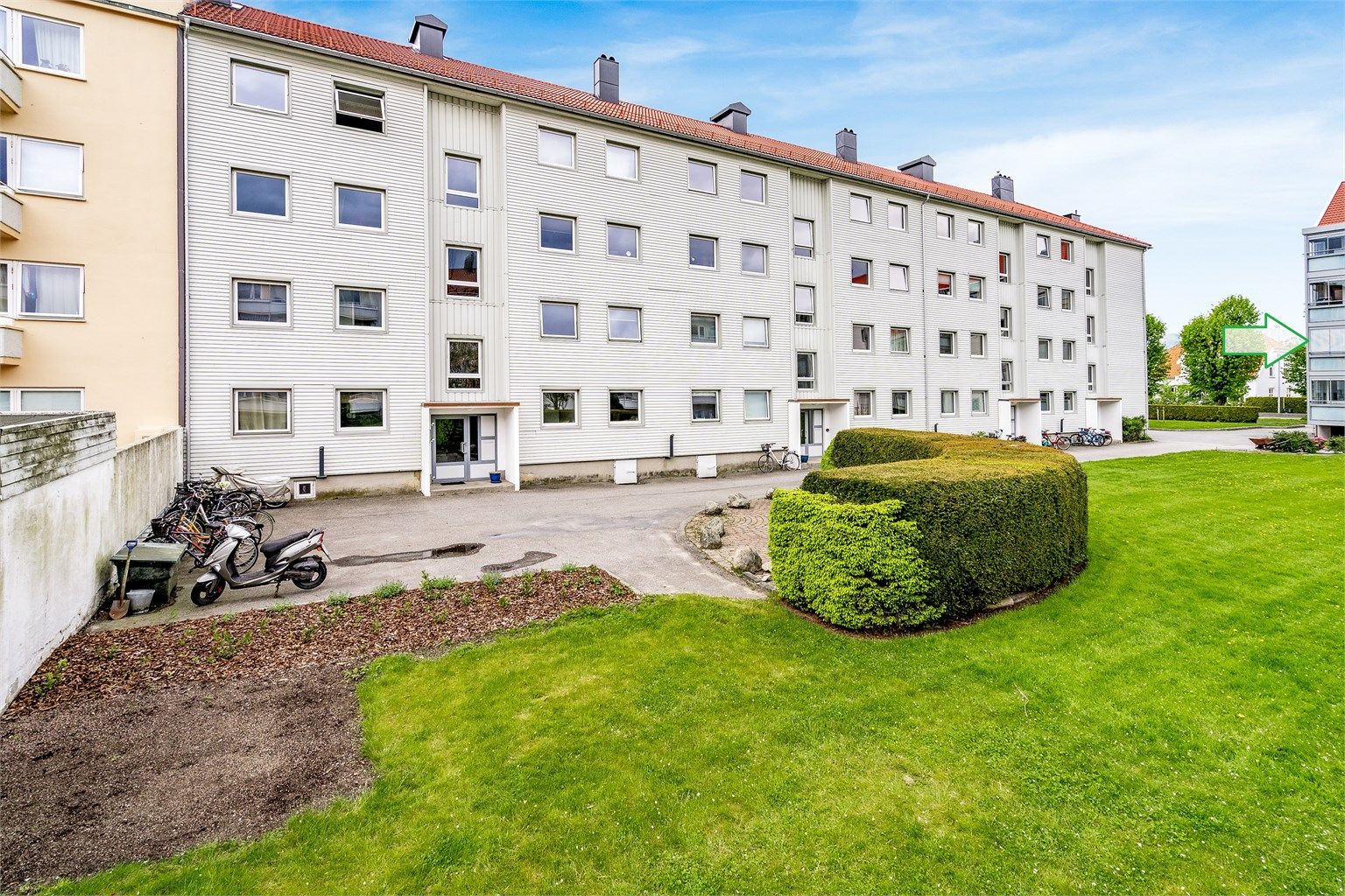 Fellesareal med benk og sykkelparkering. Pil markerer leilighetens plassering