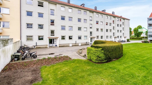 Fellesareal med benk og sykkelparkering. Pil markerer leilighetens plassering