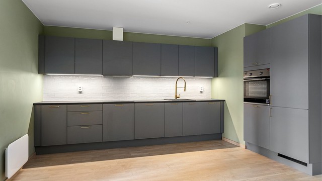 Lysarmaturer under overskap. Flislagt felt på vegg over benkeplate av laminat.