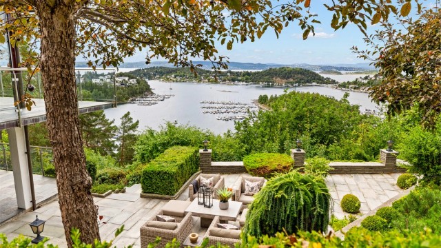 Terrassert tomt som er parkmessig opparbeidet med store skiferbelagte markterrasser, belysning, store bed med prydbusker og et lite flatt plenareal