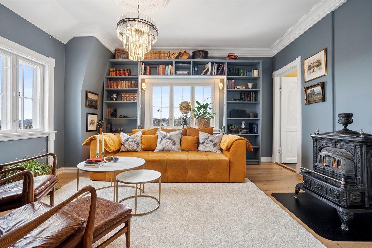 Lys stue med peisovn og plassbygget bokhylle.