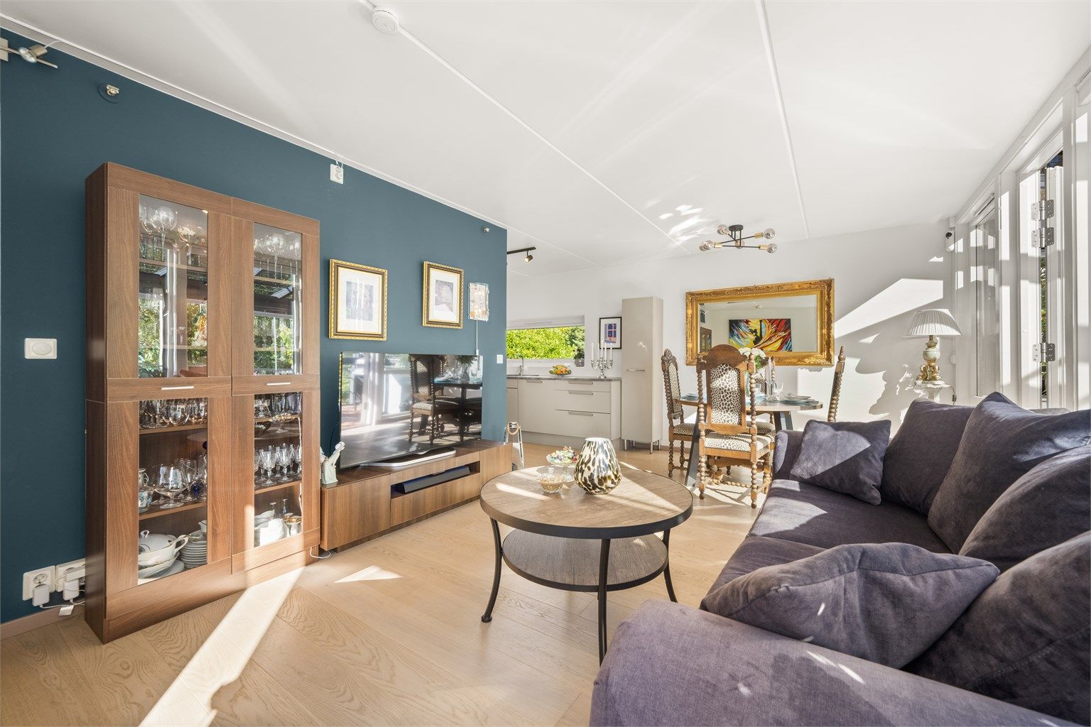 Romslig stue med plass til sofagruppe, tv-møblement og en større spiseplass.