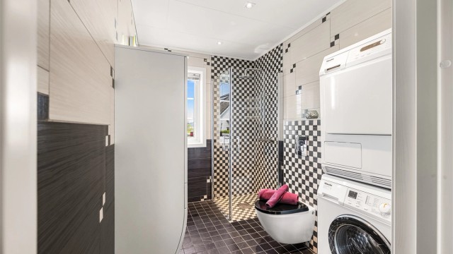 Badet i 1. etasje er flislagt og innredet med dusjsone, vegghengt toalett samt mulighet for å etablere vaskemaskin og tørketrommel.