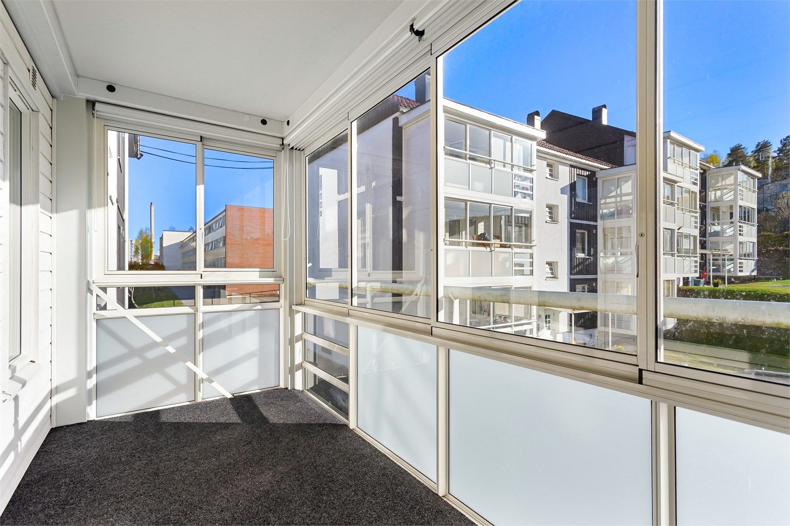 Den innglassede balkongen på 9 m² har skyvedører i glass, noe som utvider bruksmulighetene gjennom sesongene.