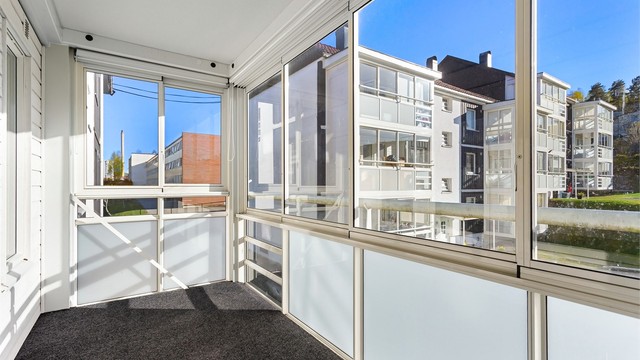 Den innglassede balkongen på 9 m² har skyvedører i glass, noe som utvider bruksmulighetene gjennom sesongene.