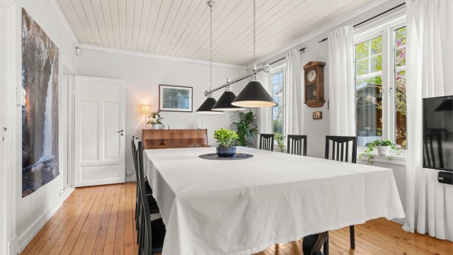 Gjennomgående store vinduer, tregulv og panel i himlingen understreker boligens klassiske preg.