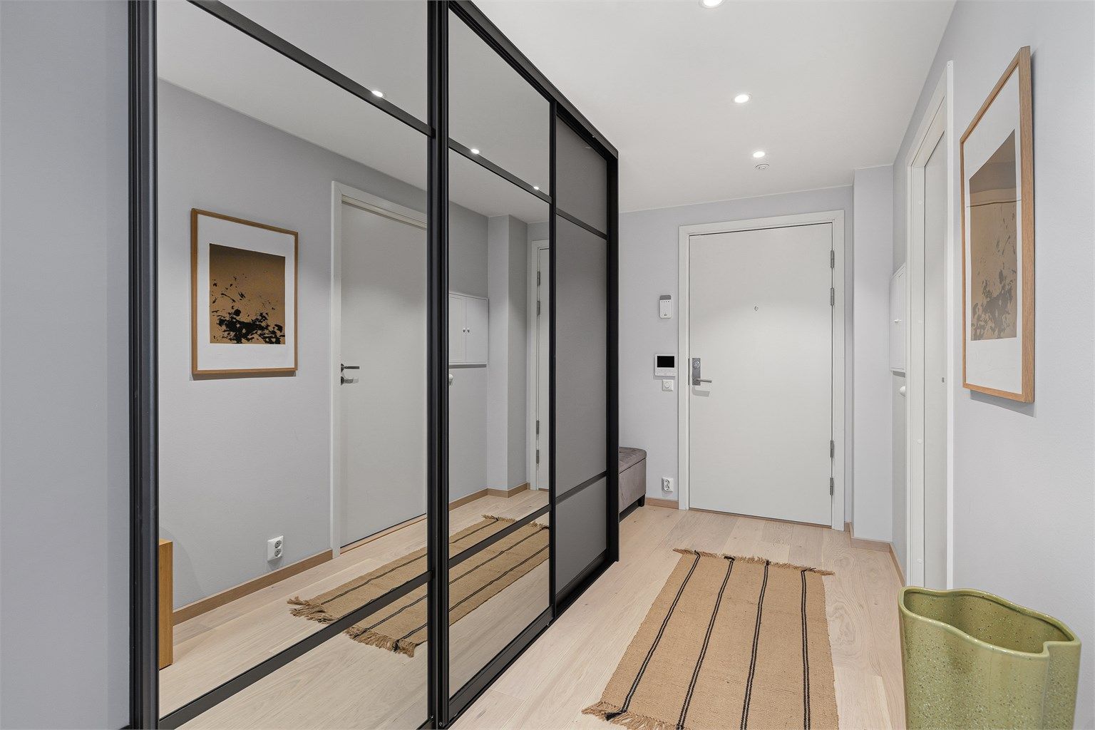 Du blir tatt i mot i en svært romslig gang med skyvedørsgarderobe fra garderobemekka hvor du kan henge fra deg klær og sette fra deg sko. Du har også plass til en benk.