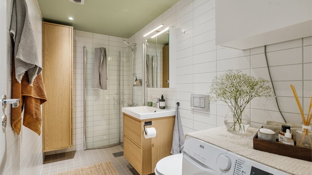 Innbydende og meget romslig bad med lyse fliser, varmekabler i gulv og downlights i himling samt opplegg for vaskemaskin