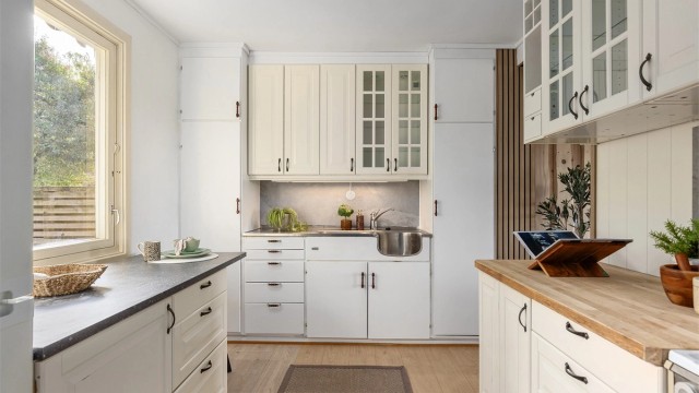 Kjøkkeninnredningen byr på rikelig med skap- og benkeplass, med profilerte og slette fronter samt benkeplater i laminat og treverk