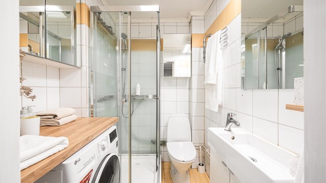 Flislagt bad med varmekabler i gulv, innredet med vegghengt servantinnredning med ovenpåliggende vask, dusjkabinett og gulvstående klosett.