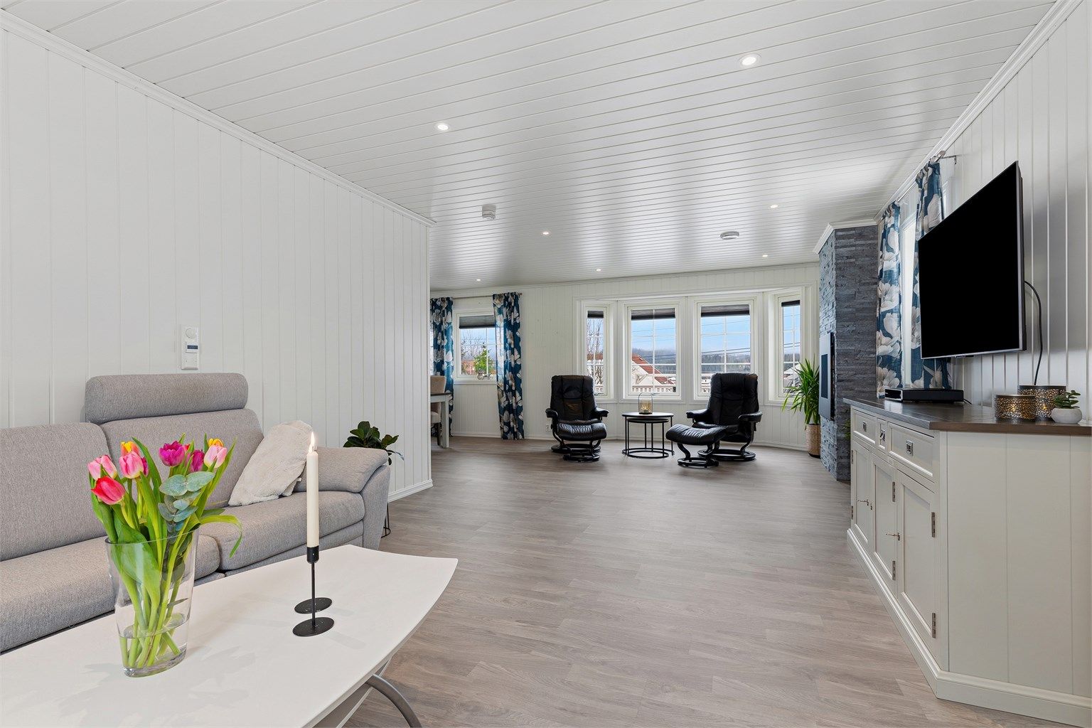 Fra stuekroken mot plass for sittegruppe ved den dekorative og stilige gasspeisen som gir lun varme på kalde dager